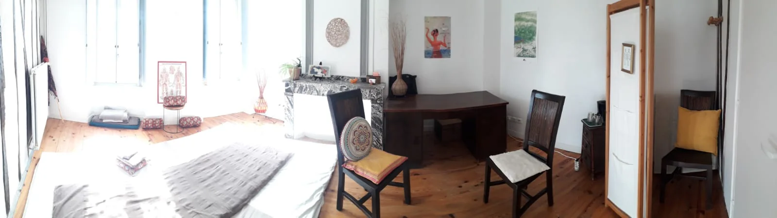 La pièce dans sa longueur : le matelas de sol devant les fenêtres, un bureau de bois et deux chaises, un paravent près de l'entrée.